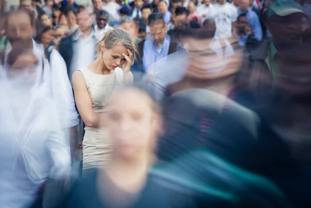 Depressed young woman feeling alone amid a crowd of people in a