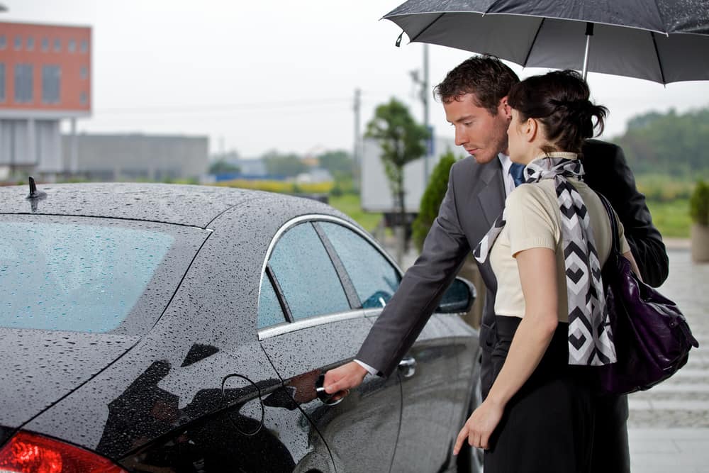 Young man opening door of car for woman