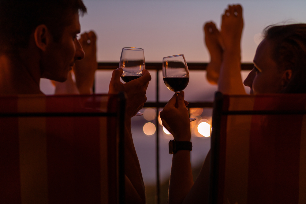 Romantic couple talking and have wine at sea view terrace at sunset. Valentine day image